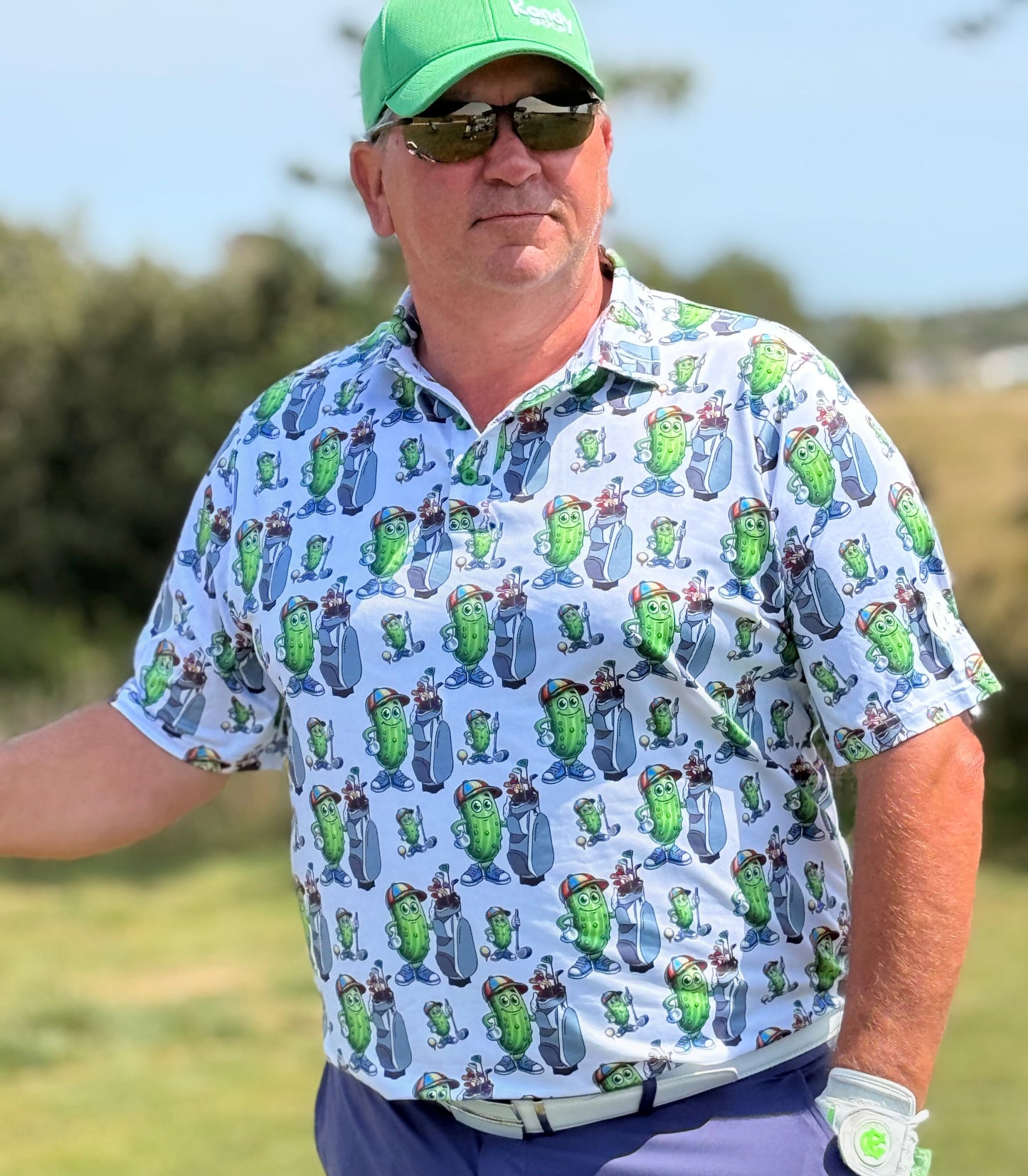 Man wearing a patterned shirt and green cap on a golf course